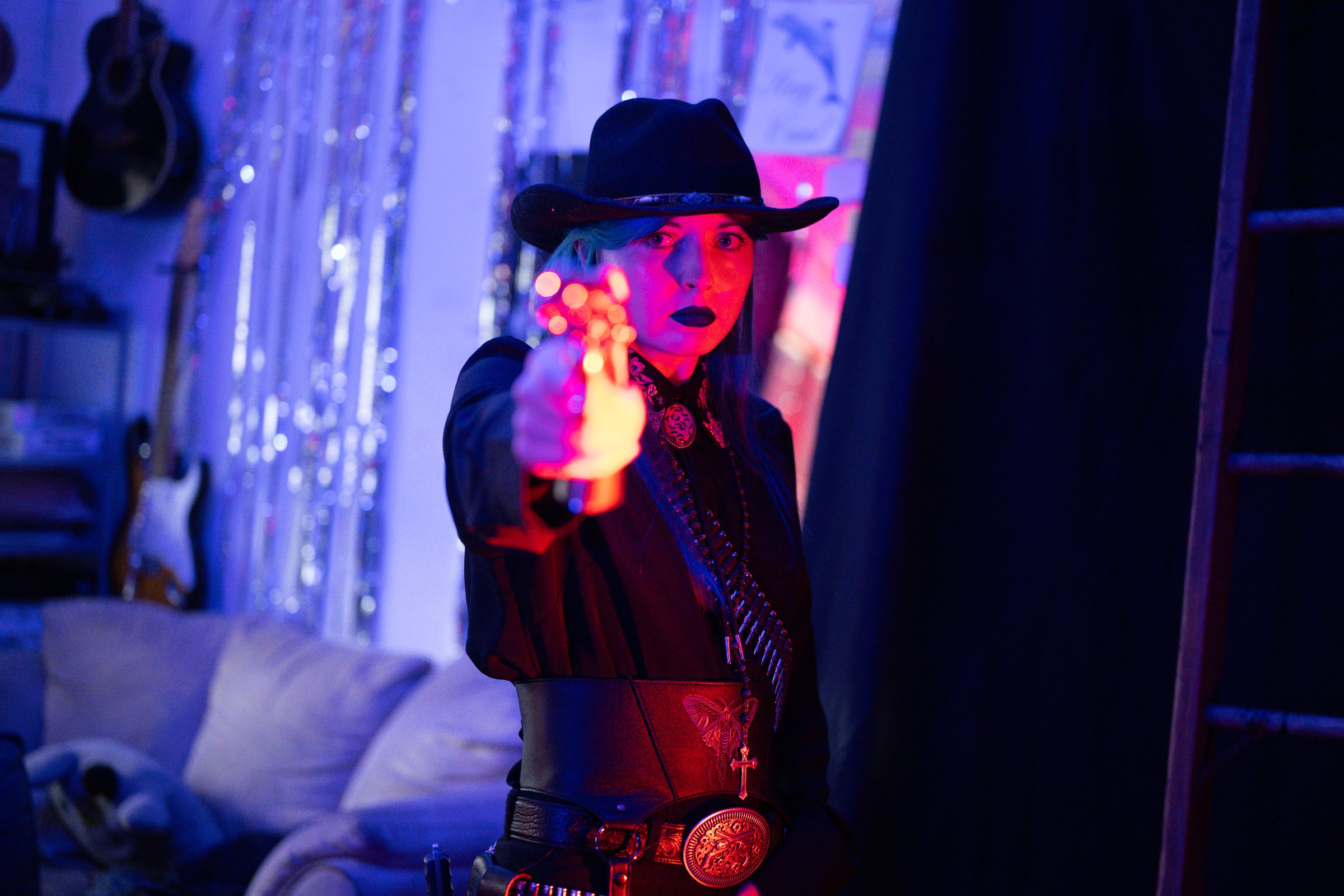 Gothic Country, model aiming a revolver toward the camera in red and blue light