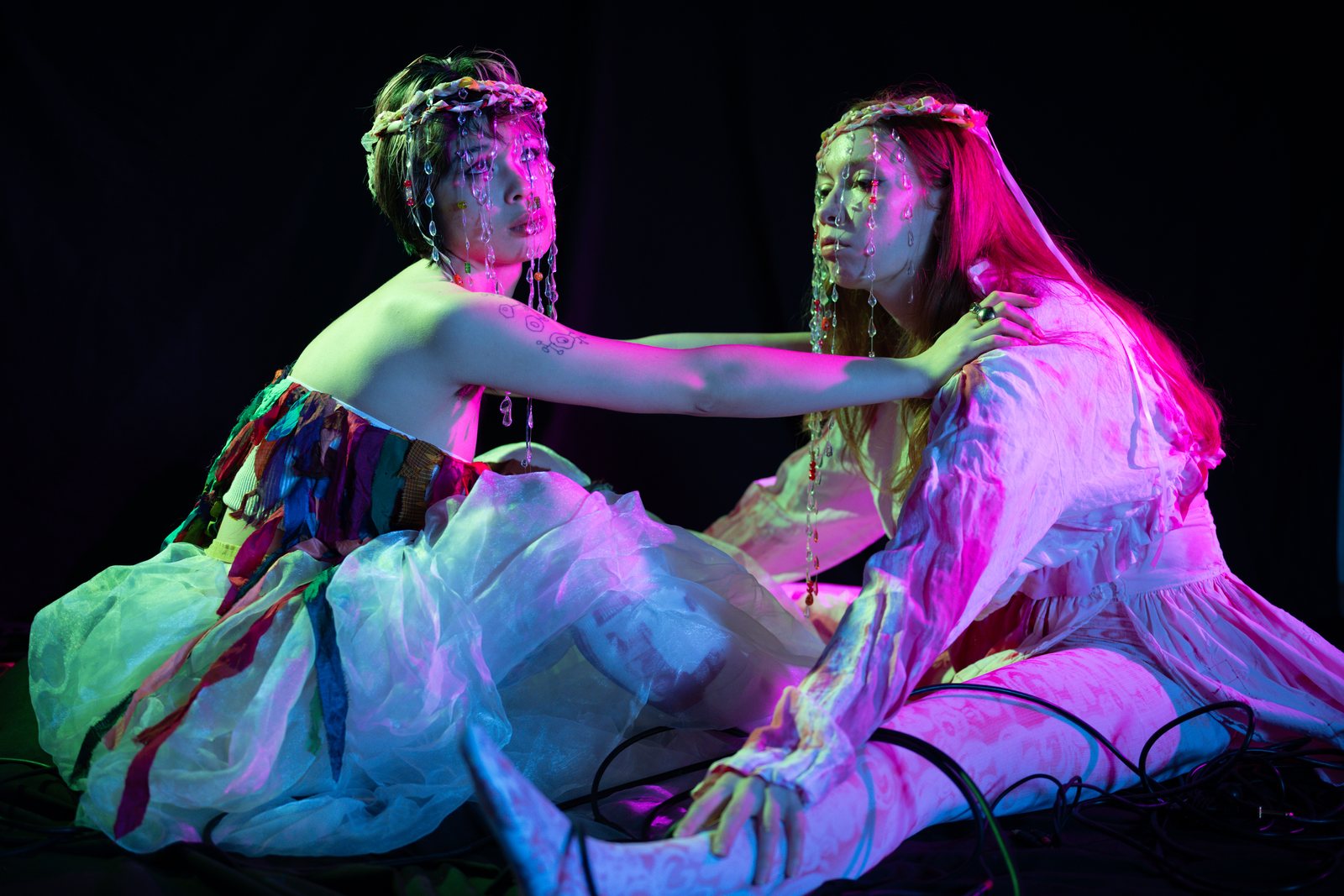 Post Apocalypse, two models on the floor in magenta light
