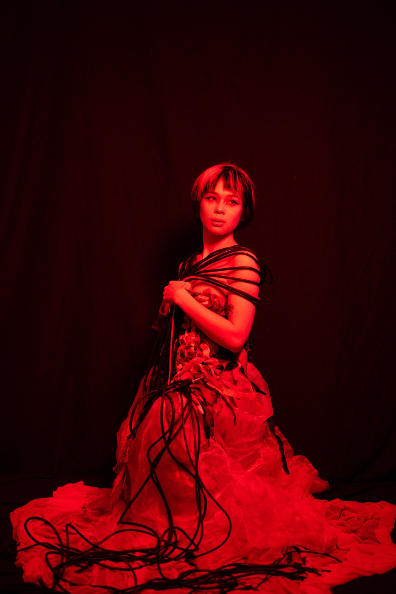 Post Apocalypse photoshoot, model in red light with the gown train